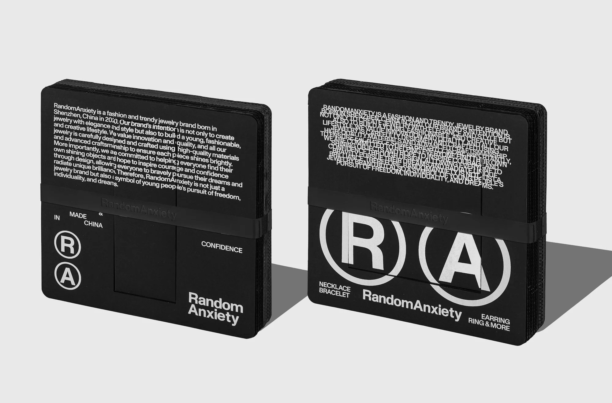 Two black jewelry product display cards with text and logos in a minimalist presentation, showcased against a neutral backdrop.