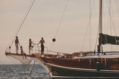 Group of models standing on the bow of a wooden sailboat on the ocean for the Brunello Cucinelli campaign