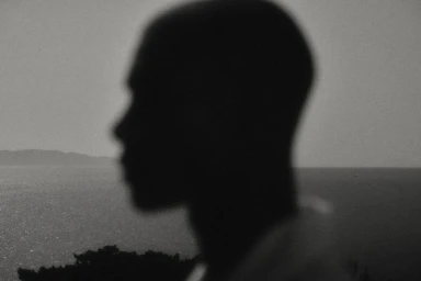 Monochrome close-up profile silhouette of a model overlooking the sea for the Brunello Cucinelli Spring-Summer 2025 campaign.