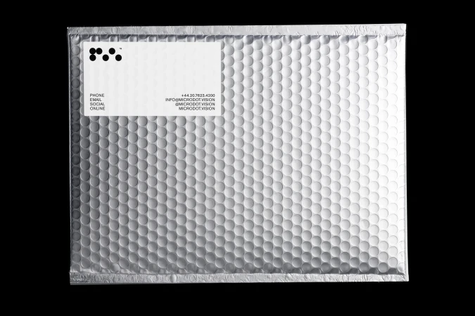 Metallic bubble mailer on a black backdrop. Features a white label with black text and dots for a modern, minimalist aesthetic.