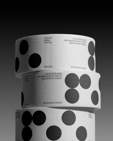 Three rolls of white tape stacked vertically with black dot pattern and text: phone, email, social, online, and microdot vision.