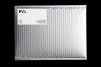 Silver bubble mailer packaging with a white label displaying Microdot branding and contact details against a black background.