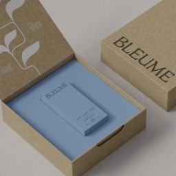Open brown craft paper box with white botanical illustrations and a blue plant food product resting on a matching blue insert inside.