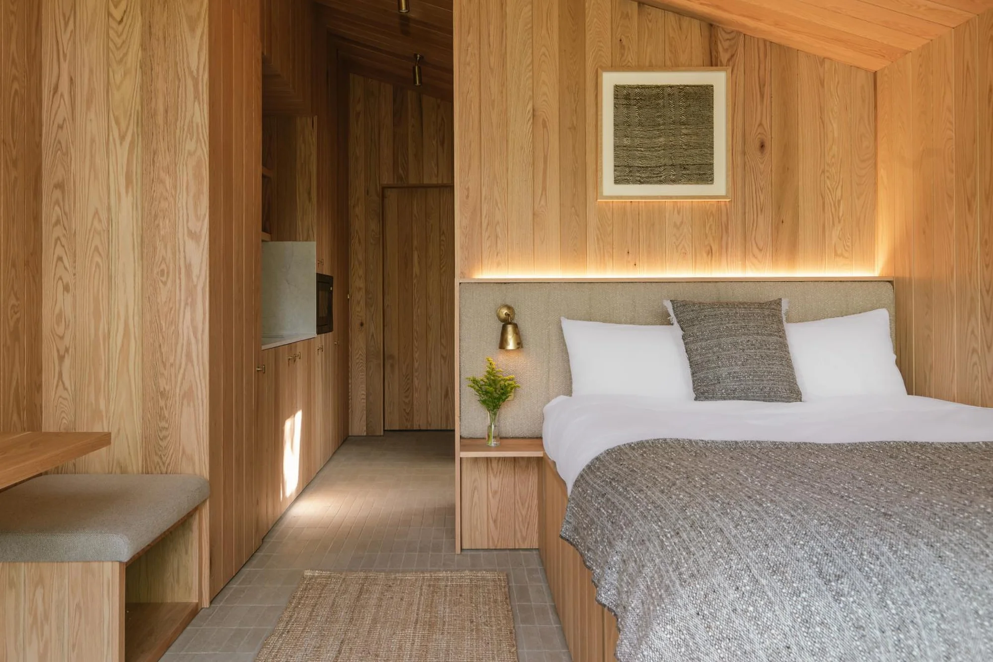 Cozy interior design featuring a bed, wood paneling, and warm lighting in a small space, creating an inviting, modern architectural aesthetic.