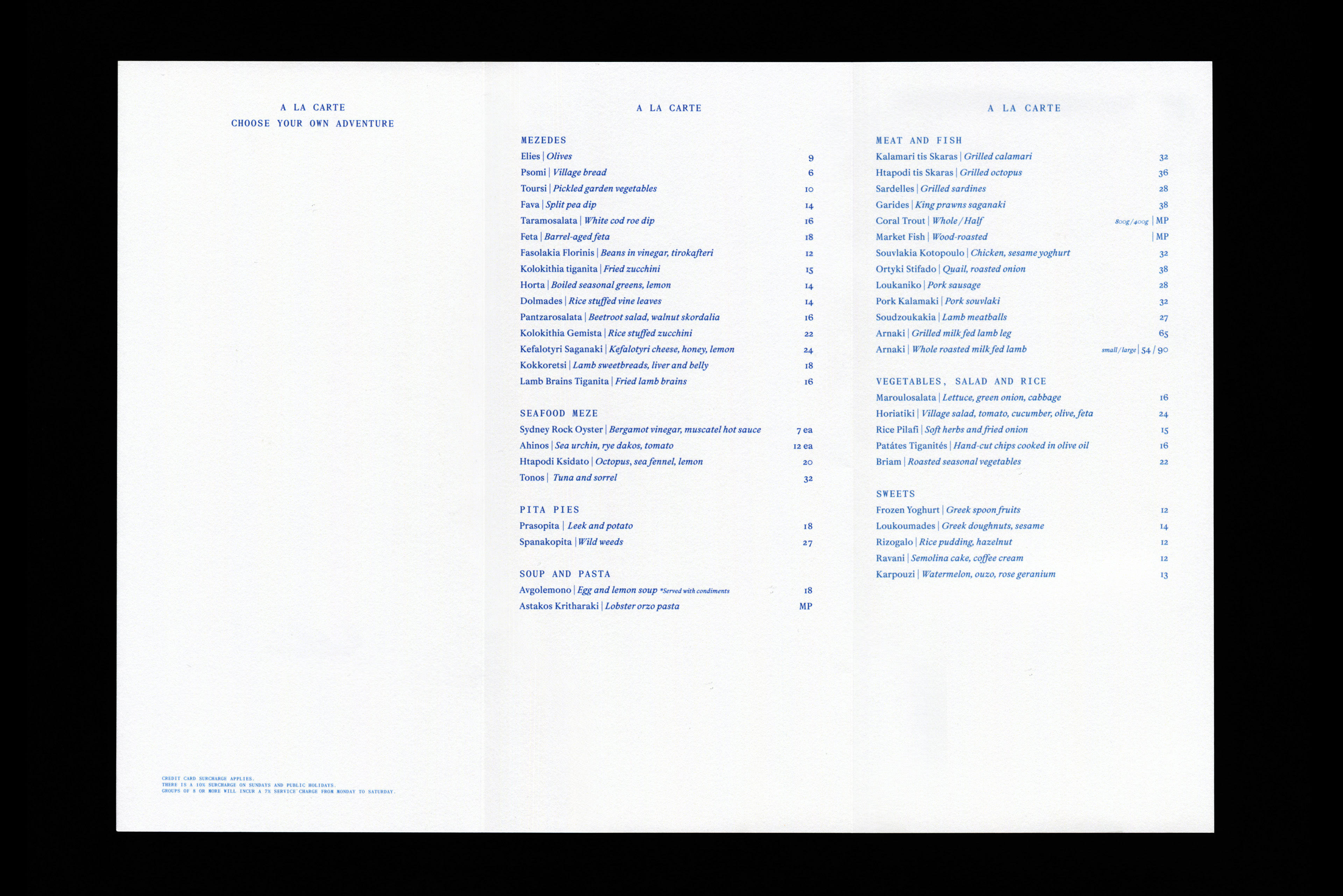 Bright studio shot of a tri-fold restaurant menu with Greek cuisine options including seafood, meat, vegetables, and desserts in blue ink.