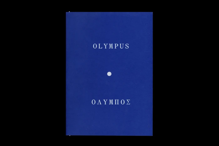 Blue book cover featuring centred white typography reading OLYMPUS and Greek lettering with a small dot below