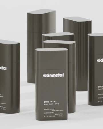 Multiple dark grey Skinmetal sunscreen bottles arranged in a studio product display against a pale background
