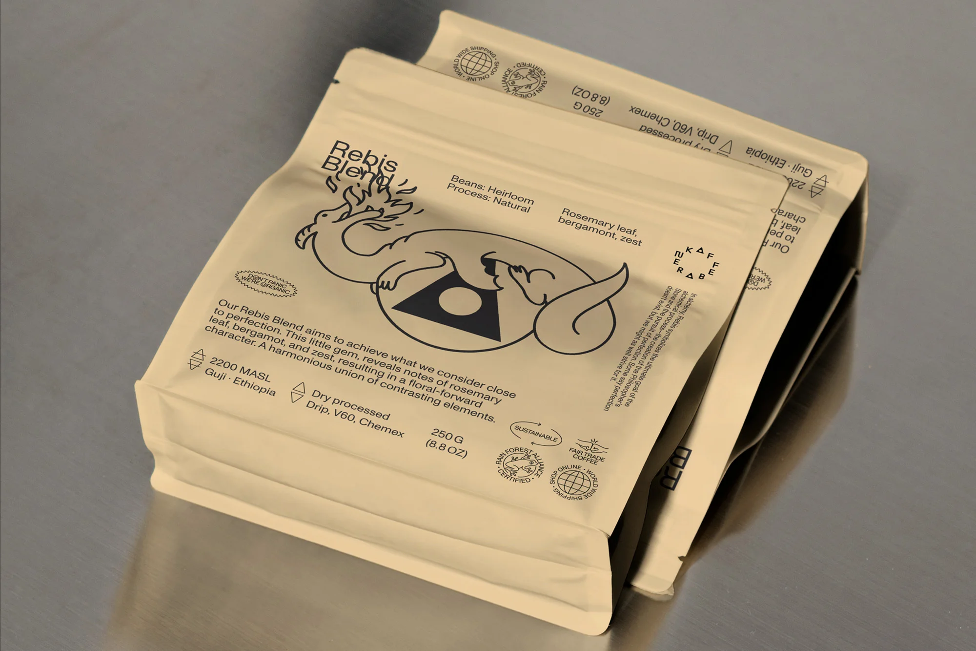 Close-up studio shot of two Rebis Blend coffee bags. Packaging features dragon illustration, origin information, and sustainability certifications.