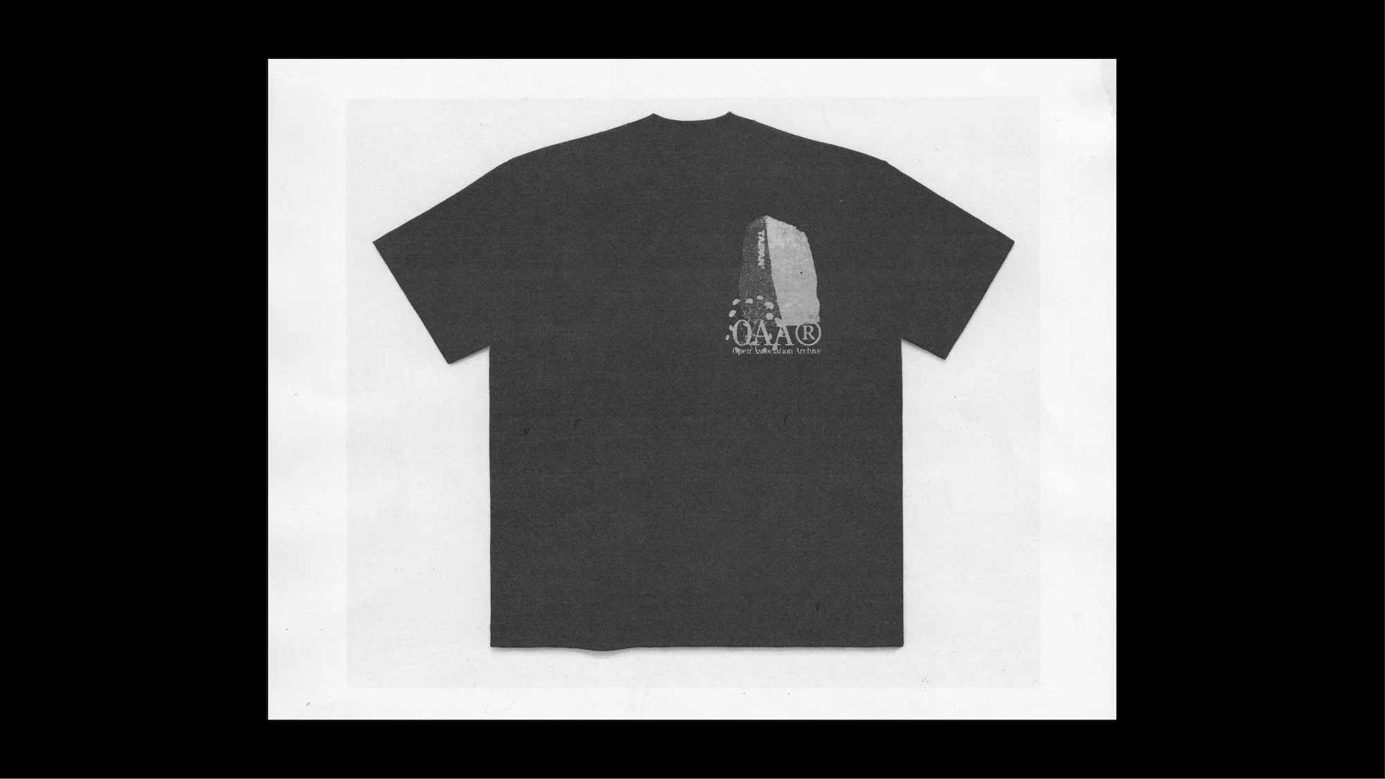Dark t-shirt with logo in a studio setting. The logo features a stone monument design with text, displayed on a white backdrop.