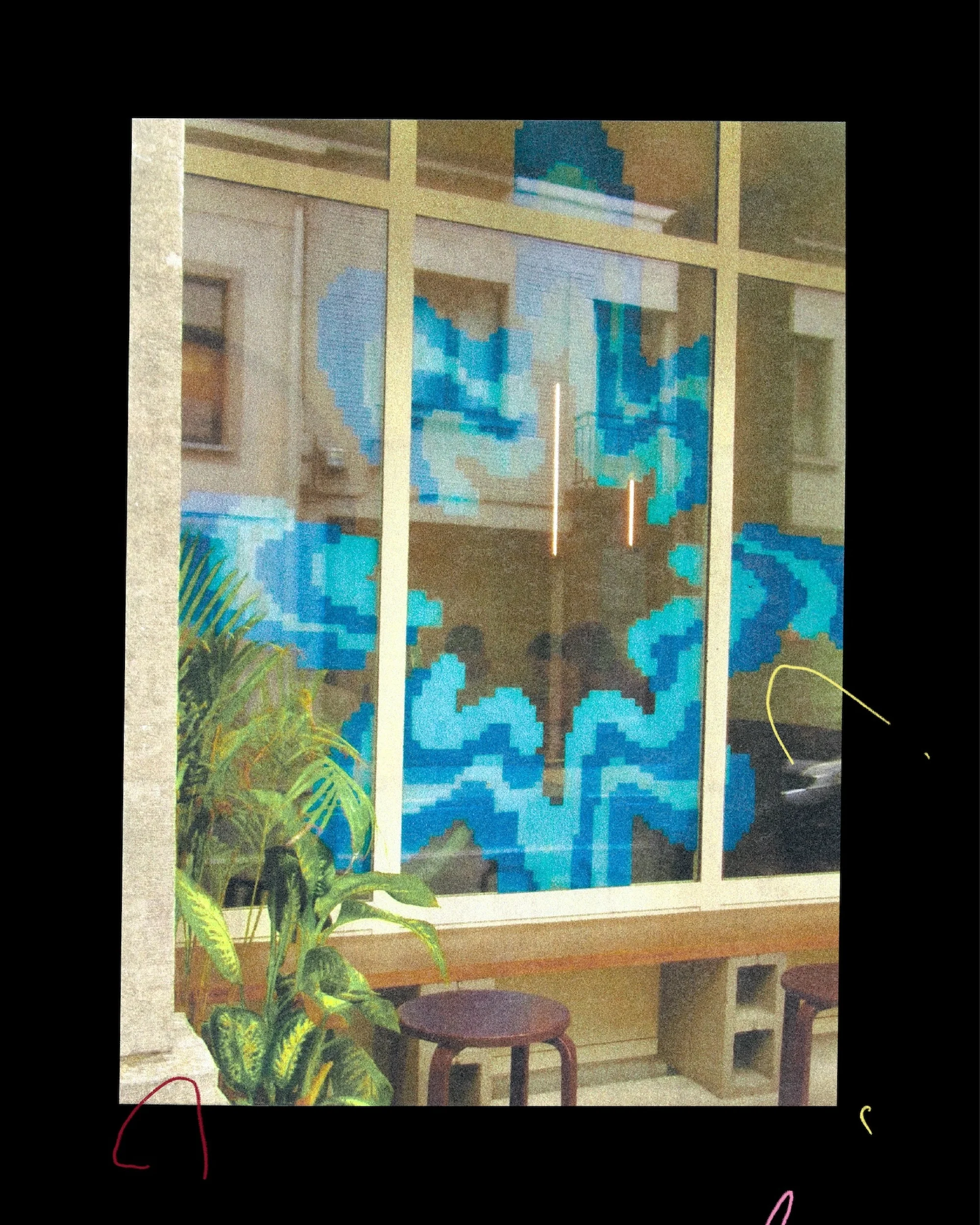 Outdoor cafe seating with stools and a lush potted plant in front of a window displaying a pixelated graphic design in blues and greens.