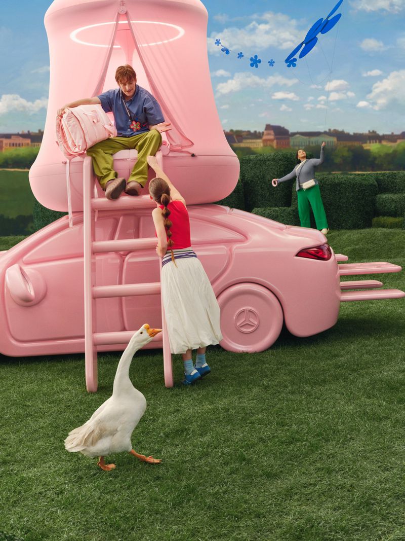 Whimsical outdoor scene featuring people and a white goose near a pink car-shaped structure with ladder and tent under a blue sky.