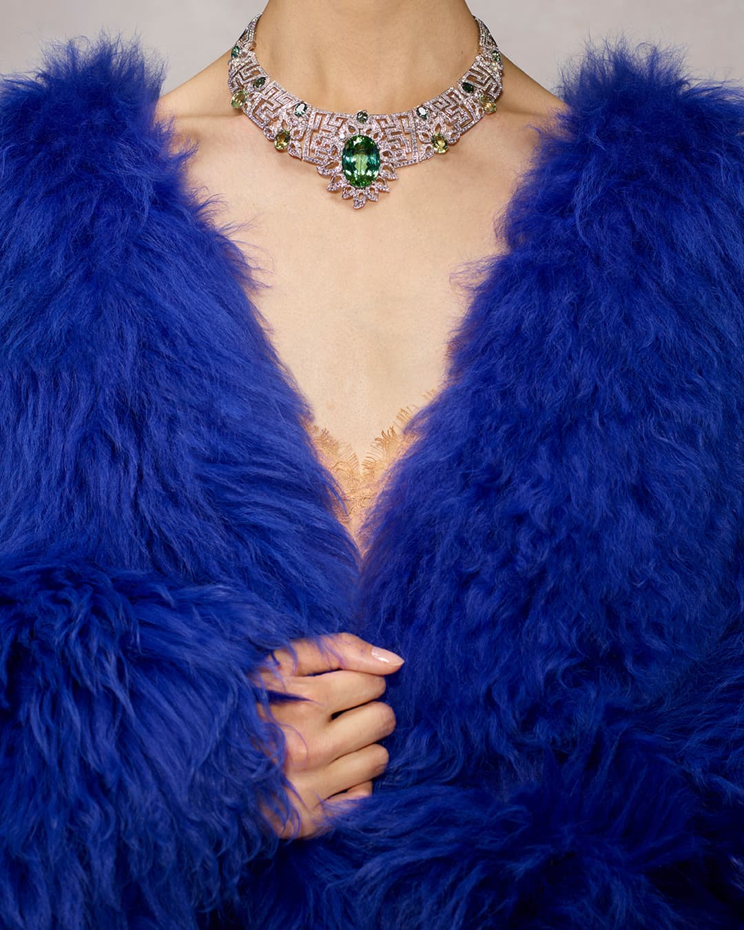 Close-up of a person wearing a fur coat and an ornate gemstone necklace, showcasing fashion, jewelry, and luxurious textures.
