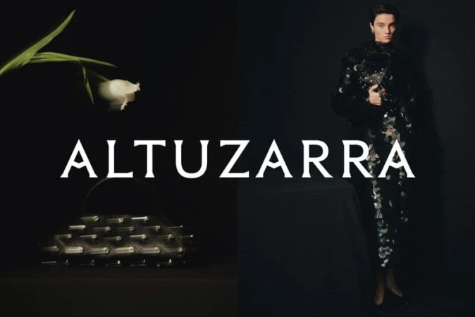 Model wearing dark textured clothing and holding a handbag next to a white tulip on a dark background for the Altuzarra campaign.