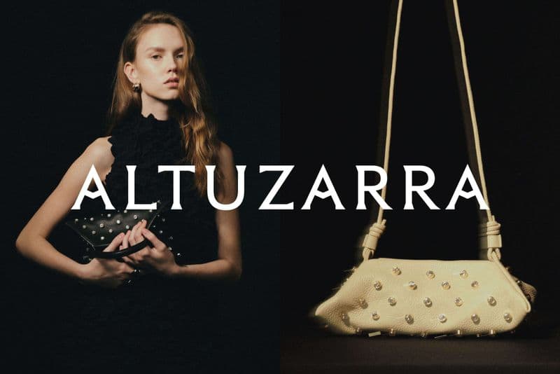 A woman with long hair poses in front of a black background, holding a black clutch with metal studs. A cream-colored bag with studs is next to her.