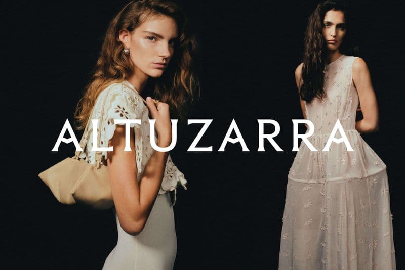 Two fashion models wearing dresses against a dark background. One model is holding a light-brown purse, and a brand name is displayed in the image.
