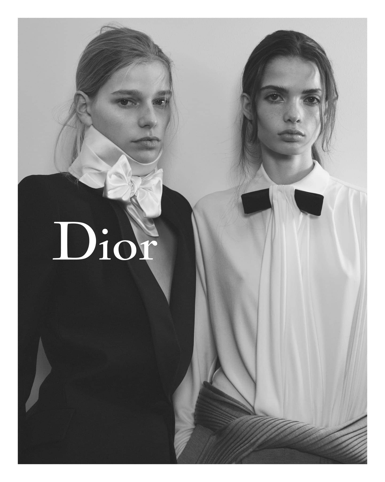 Black and white portrait of two young women wearing elegant attire and prominent neckwear, showcasing high-fashion design.