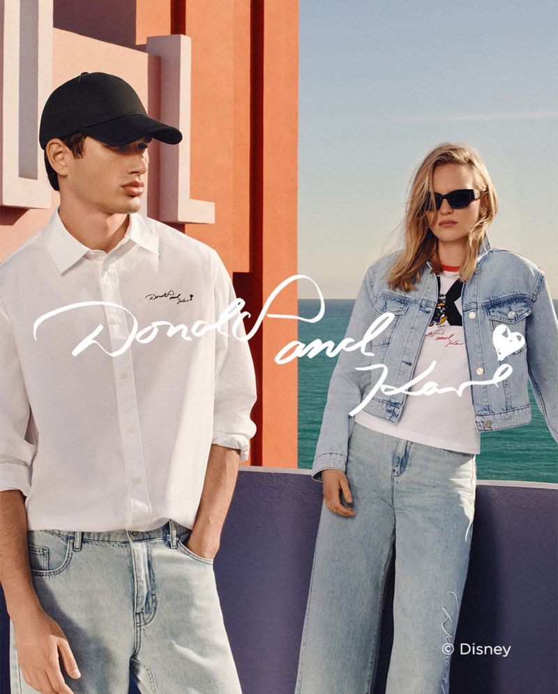 Two fashion models pose outdoors in casual denim and shirts with a blue ocean backdrop, showcasing youthful, summery apparel.