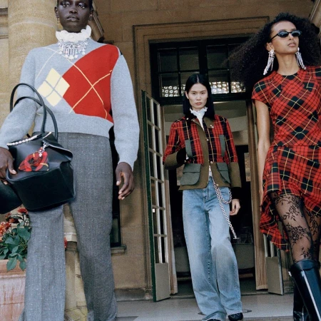 Three models in tartan and argyle fashion outside a stone building for McQueen