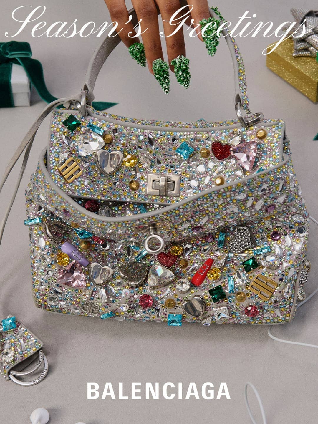 Embellished Balenciaga purse with ornate silver hardware, rhinestones, and heart charms set against a neutral surface near holiday-themed gift.