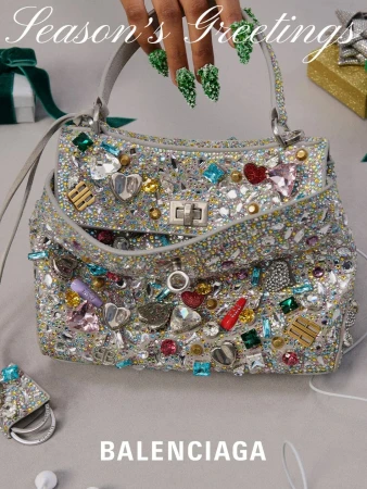 Embellished Balenciaga purse with ornate silver hardware, rhinestones, and heart charms set against a neutral surface near holiday-themed gift.