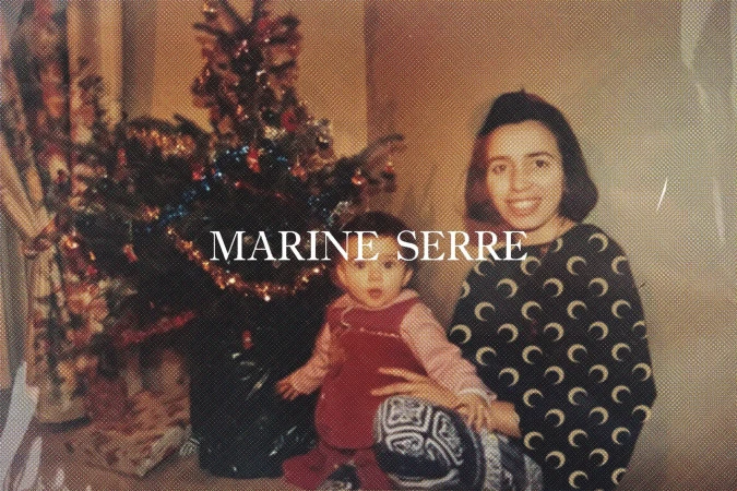 Indoor photo of a woman holding a baby near a Christmas tree with wrapped gifts, featuring a vintage aesthetic and familial warmth.