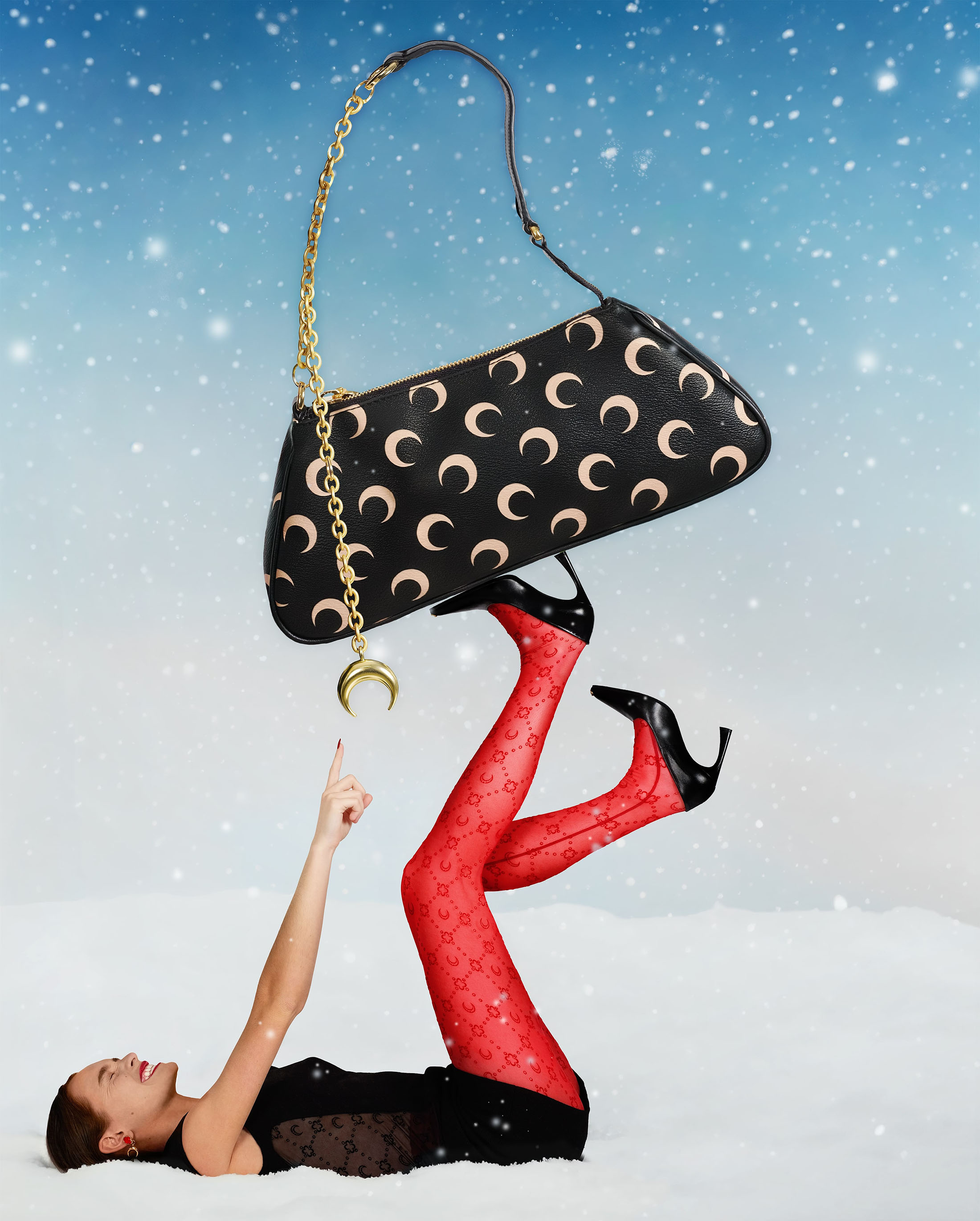 Woman in red patterned tights balances a black moon-patterned purse on her feet in a surreal snowy landscape under a bright sky.