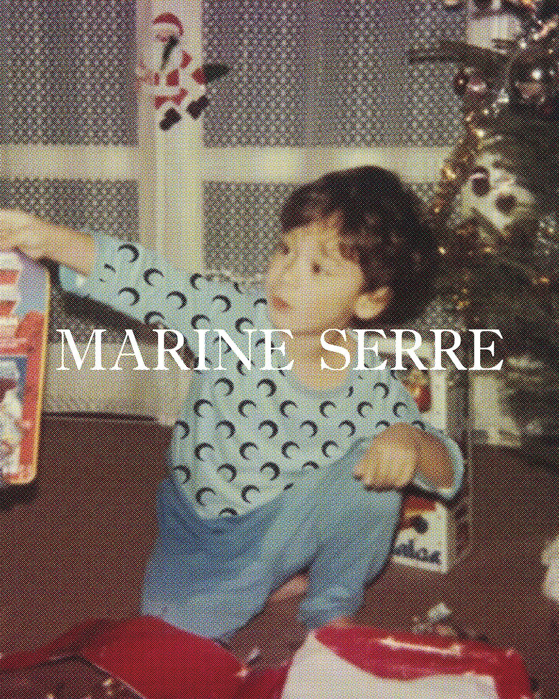 Young child in patterned pajamas seated by open gifts near a decorated Christmas tree, captured in a snapshot style photograph.