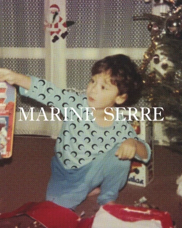 Young child in patterned pajamas seated by open gifts near a decorated Christmas tree, captured in a snapshot style photograph.