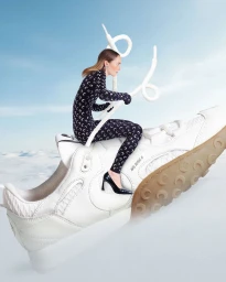 Model riding a giant white sneaker against a clear sky background for Marine Serre campaign