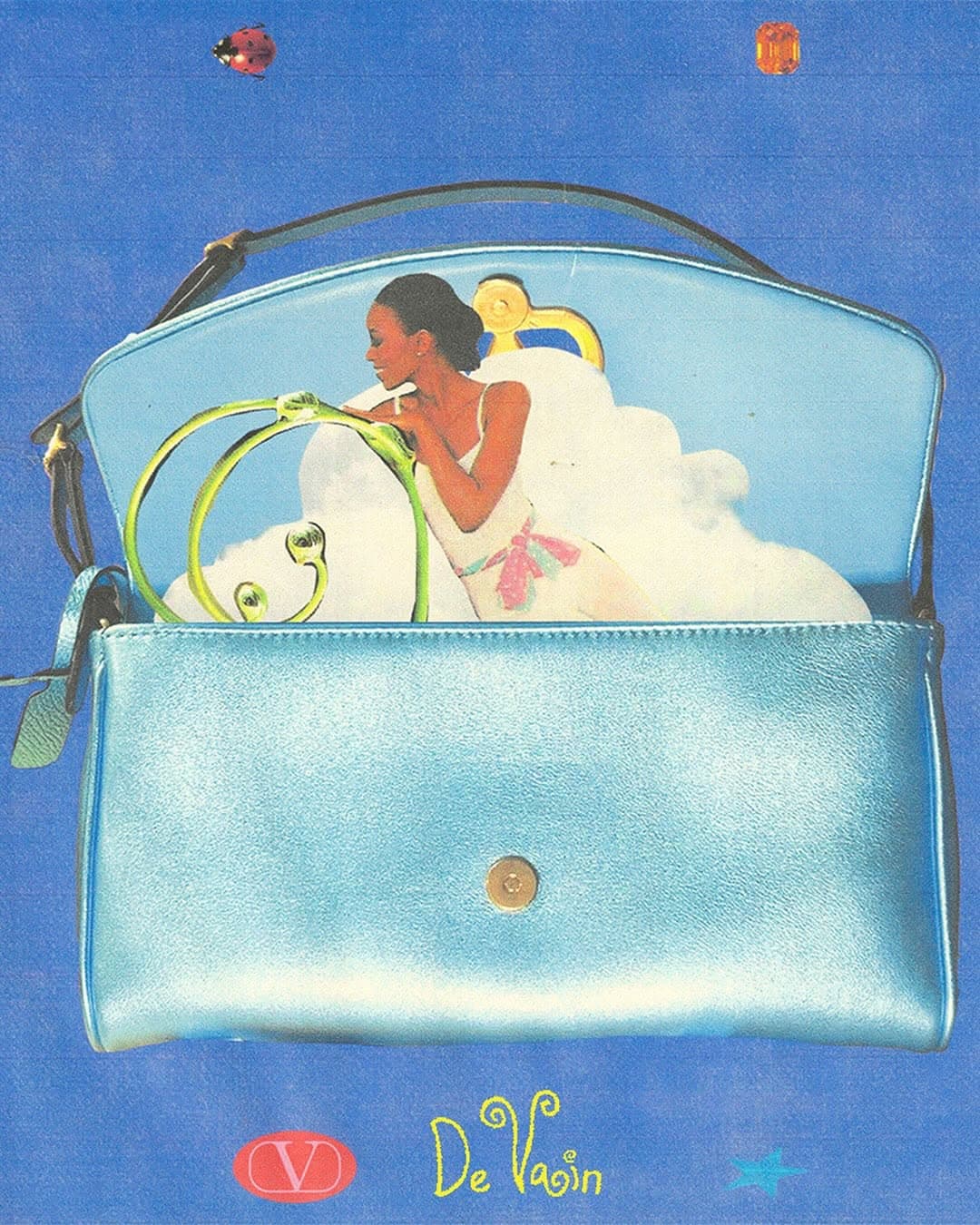 Open light blue purse with a graphic of a woman in a white dress inside against a blue background with scattered decorative objects.