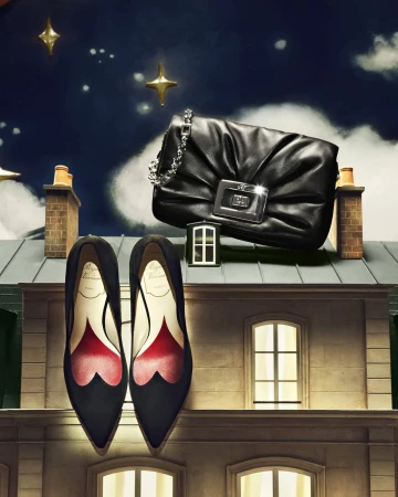 Elegant black leather handbag and high-heeled shoes displayed on a rooftop with a night sky backdrop and star accents.