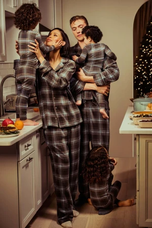 Family of five wearing matching grey plaid pyjamas in a kitchen during the holidays for SKIMS.