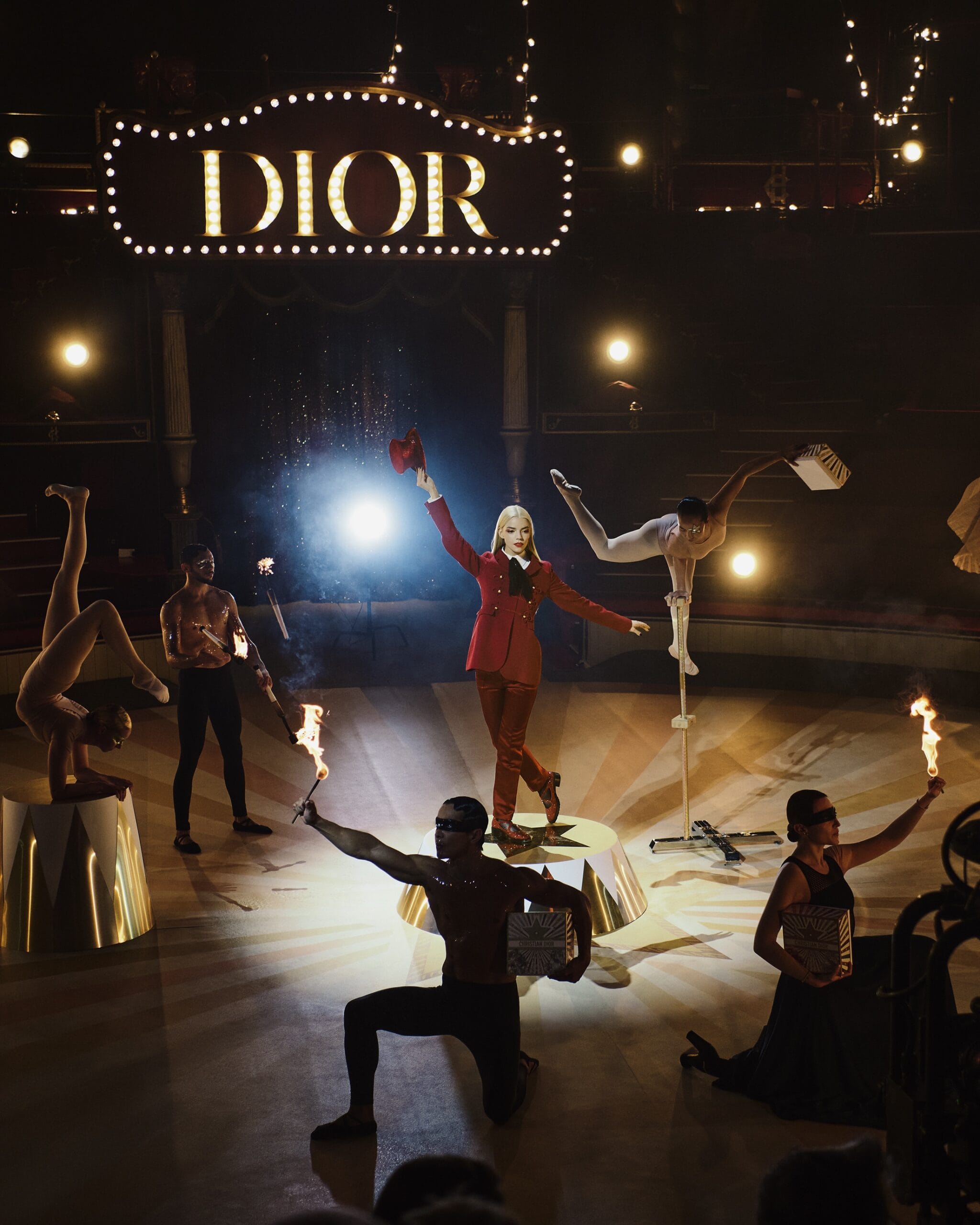 Performance art show with dancers, fire, stage lighting, and a large Dior sign. Fashion, entertainment, and visual spectacle on display.