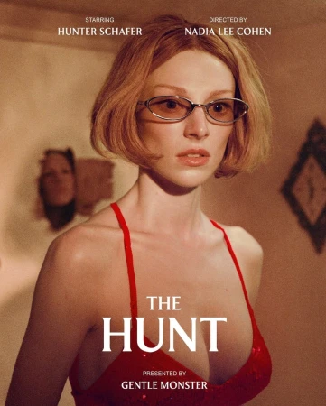 Portrait of Hunter Schafer wearing glasses and a red dress, against a textured wall with film credits in the poster for 'The Hunt'.
