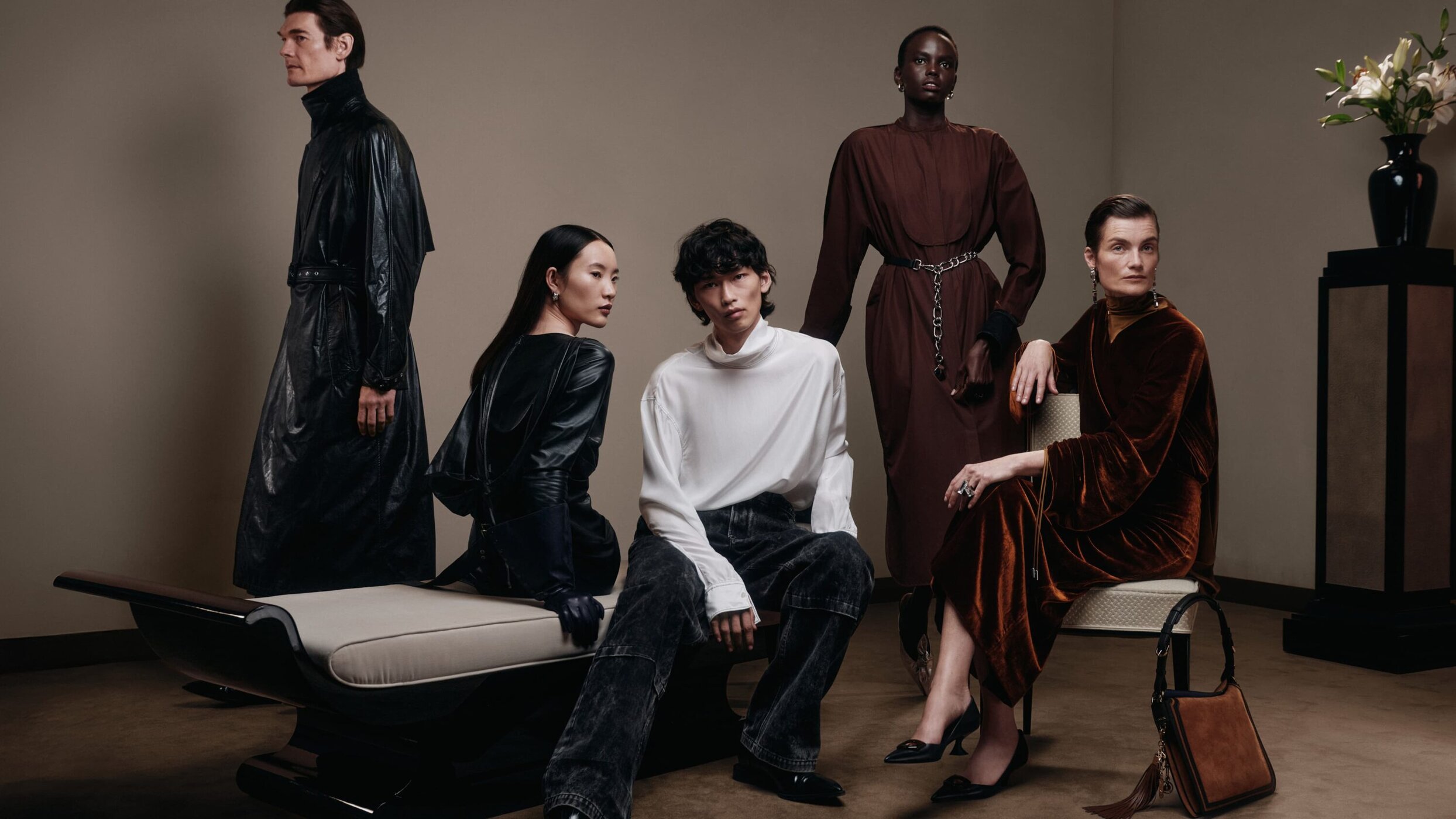 Group of five diverse fashion models posing in elegant attire in a studio setting, showcasing luxury clothing and neutral color palettes.