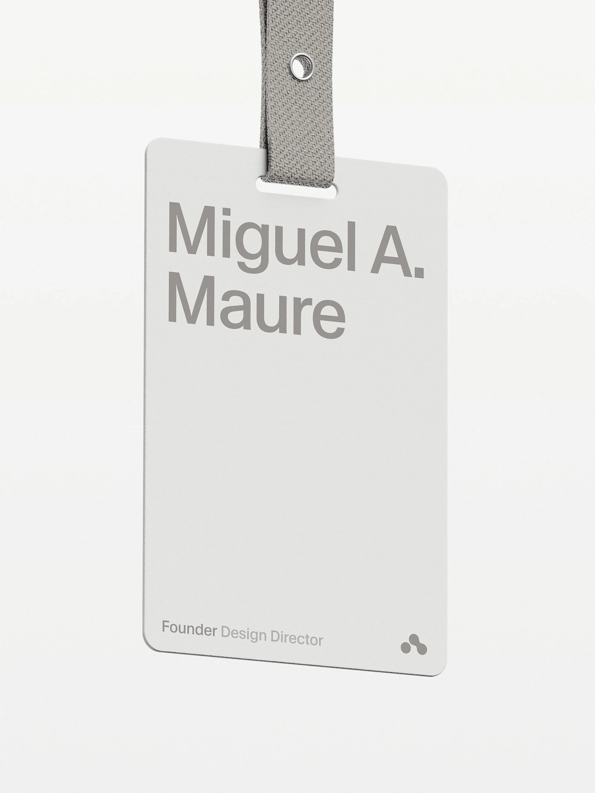 Close-up of a name tag with the text 'Miguel A. Maure, Founder Design Director' on a white card with a grey lanyard.