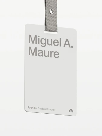 Close-up of a name tag with the text 'Miguel A. Maure, Founder Design Director' on a white card with a grey lanyard.