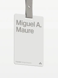 A white plastic ID badge hanging from a grey fabric lanyard against a solid neutral background.