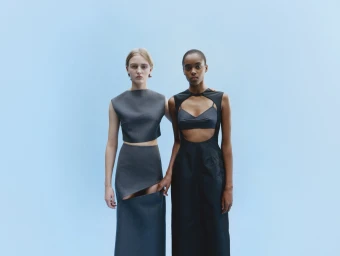 Two models standing side-by-side against a pale blue seamless background for Jil Sander ad campaign