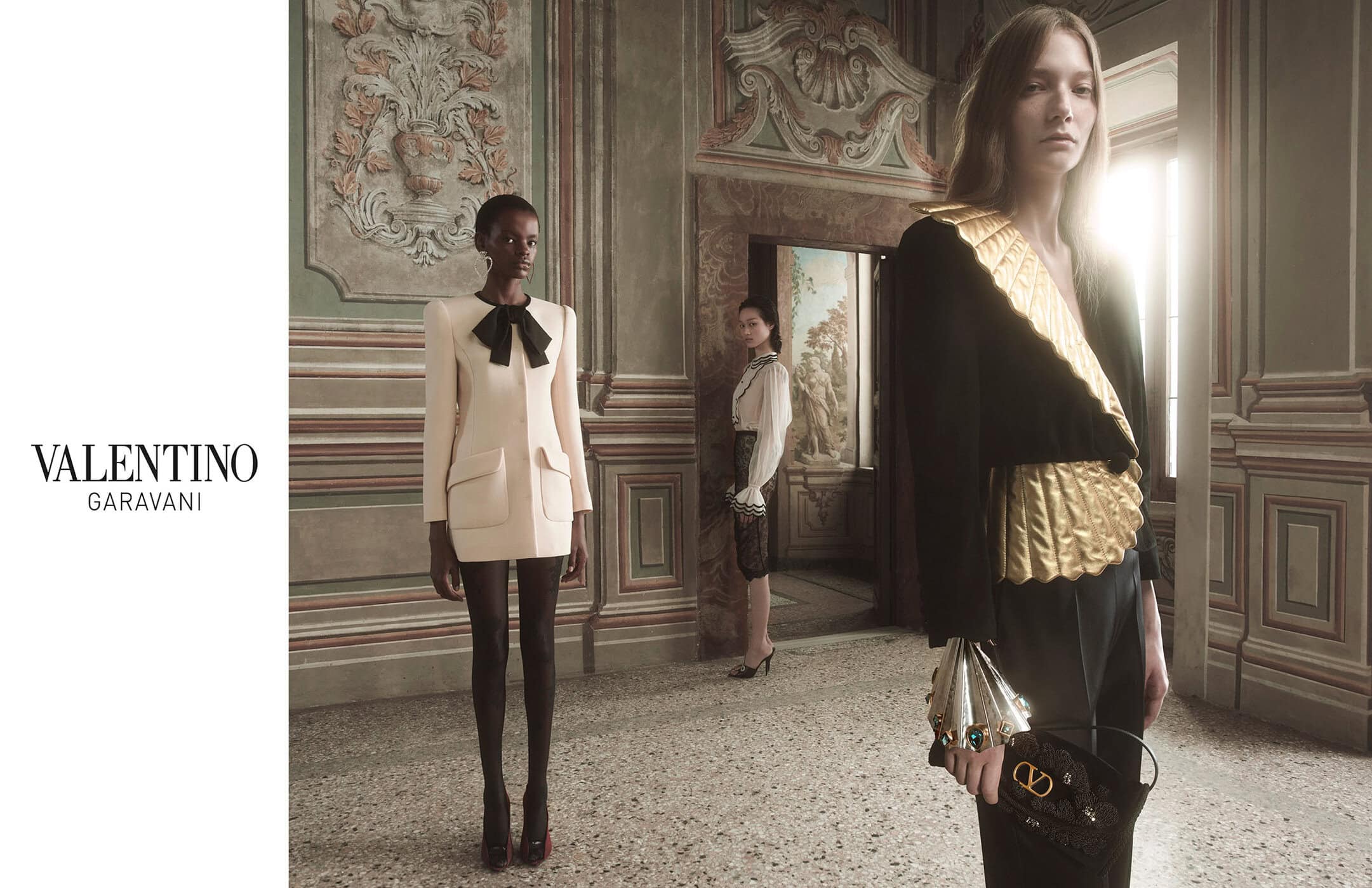 Valentino fashion shoot featuring three women in elegant dresses and accessories, set in an ornately decorated indoor location.