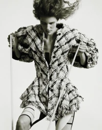 Model Rosalieke Fuchs wearing a patterned tweed jacket holding white rods against a seamless white background for Document Journal.