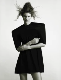 Model Rosalieke Fuchs in a black structured dress with pointed shoulders against a plain background for Document Journal.