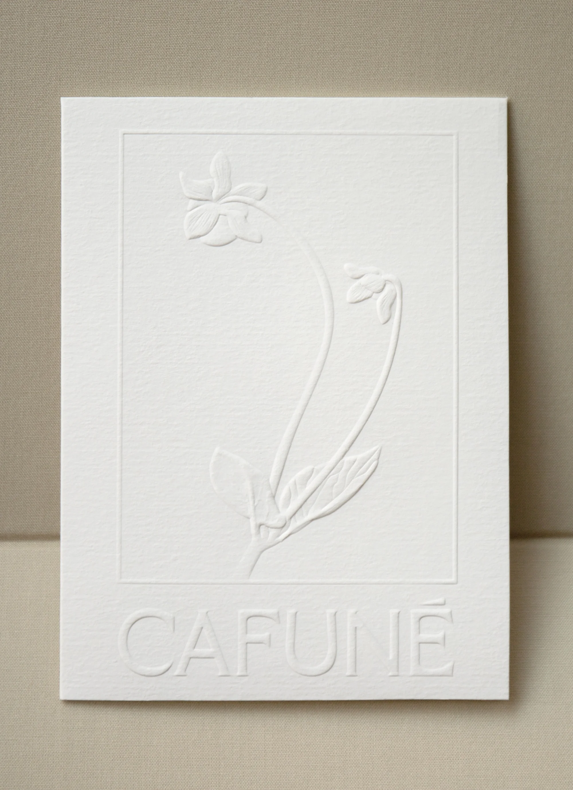 Embossed flower illustration on white paper with 'CAFUNE' text at the bottom, conveying a minimalist and textured botanical artwork.