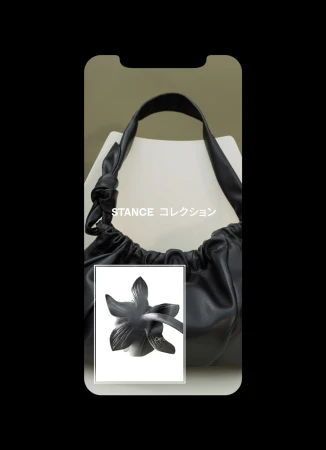 Black faux leather drawstring hobo bag with shoulder strap and flower graphic displayed on a phone screen mockup, studio shot.