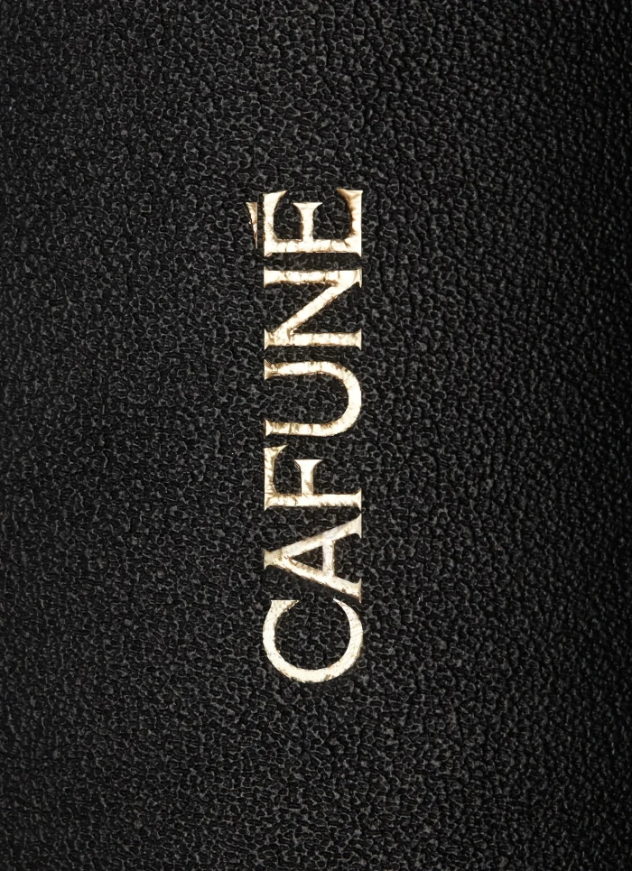 Close-up product shot of gold debossed Cafuné brand logo on black textured leather surface