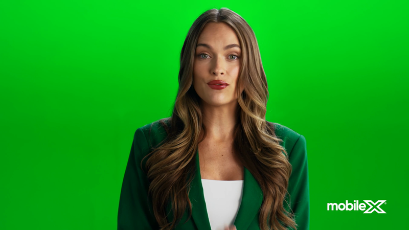 Woman in green blazer posing in front of green screen in a medium shot. MobileX logo on the lower right corner. 