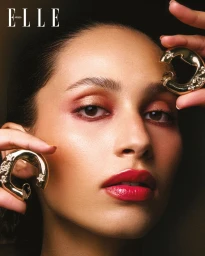 Close-up portrait of model Anissa Bakhti holding large gold hoop earrings for Elle Arabia editorial