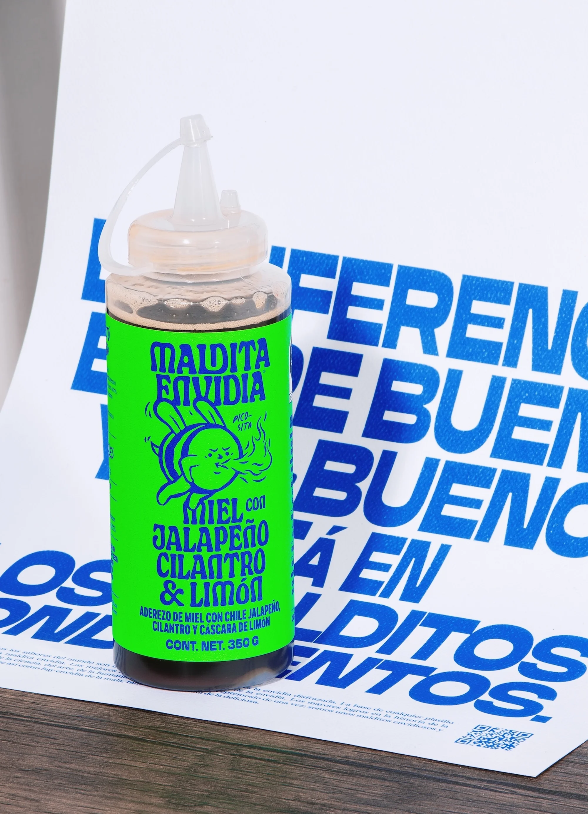 Bright green hot sauce bottle with cartoon rabbit against backdrop of blue modern sans-serif typography, product shot on tabletop.