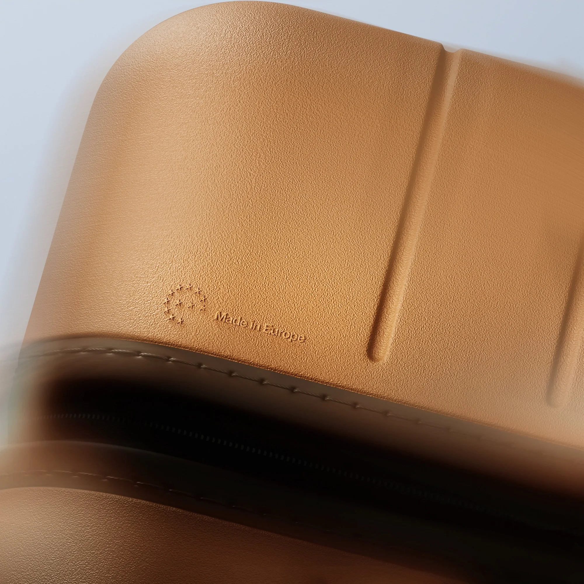 Tan luggage close-up featuring a textured shell with subtle branding that reads 'Made in Europe.'
