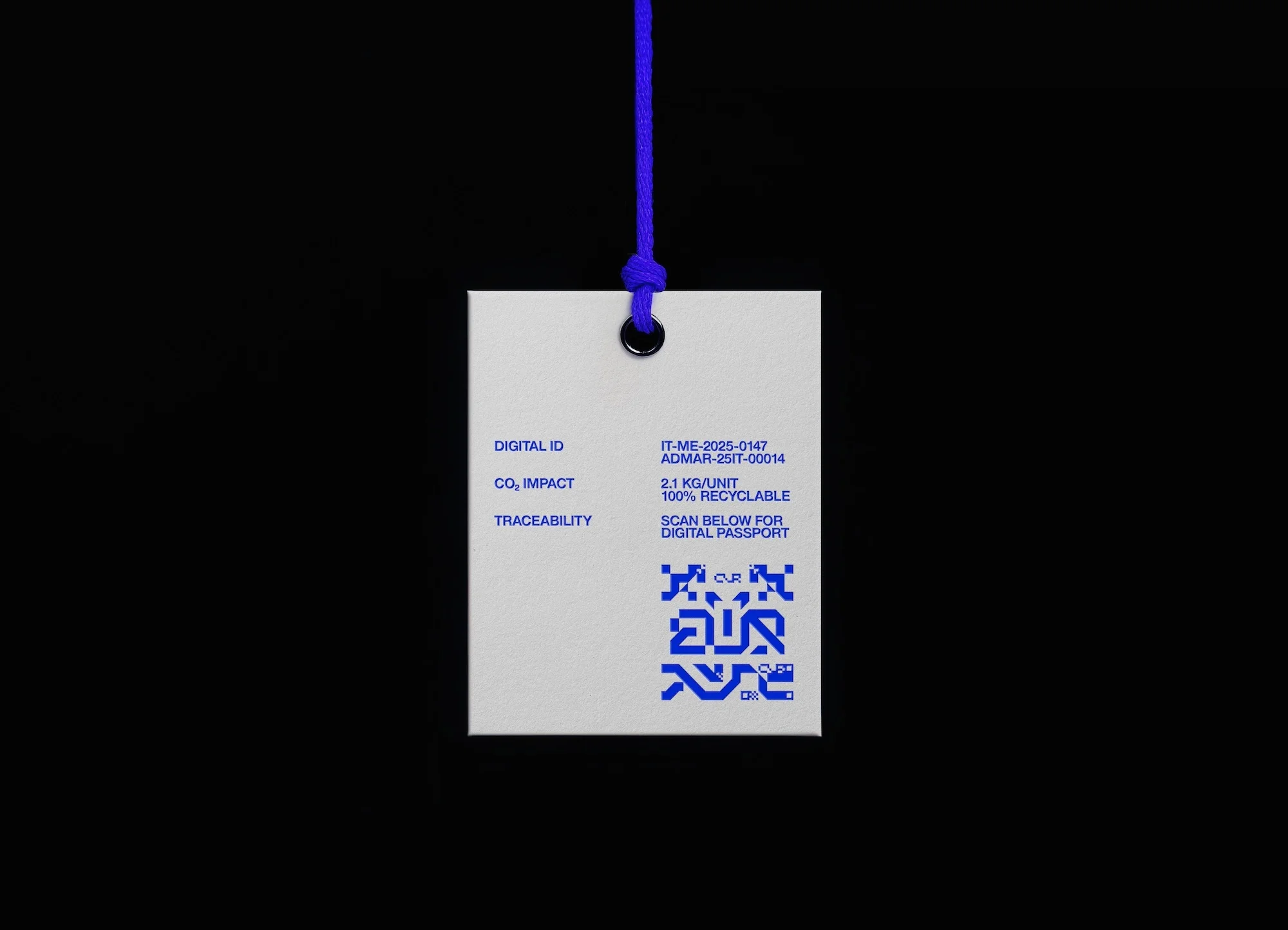 Close-up of a white tag hanging from a blue string on a black background, featuring a QR code, product information and digital ID.